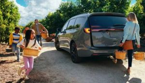 A family picking fruit at a farm, standing next to their parked 2023 Chrysler Pacifica near Anderson, Indiana.