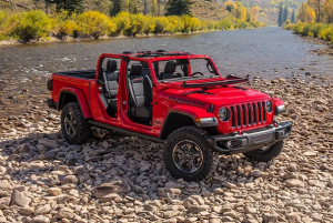 A 2024 Jeep Gladiator in red parked on a rocky shore of a river near Anderson, Indiana