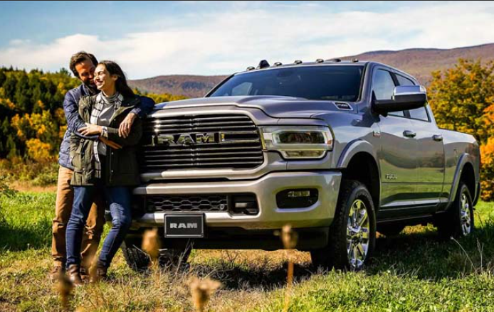 Two people standing in front of their 2024 RAM 2500, parked in a field of grass near Anderson, IN
