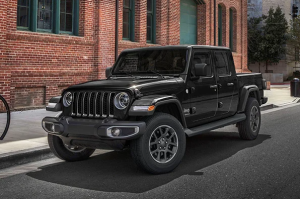 A black 2024 Jeep Gladiator parked on the side of a street. next to a brick building near Anderson, Indiana
