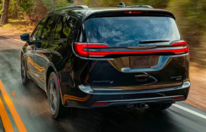A picture of a black 2024 Chrysler Pacifica driving down a wooded road near Anderson, Indiana