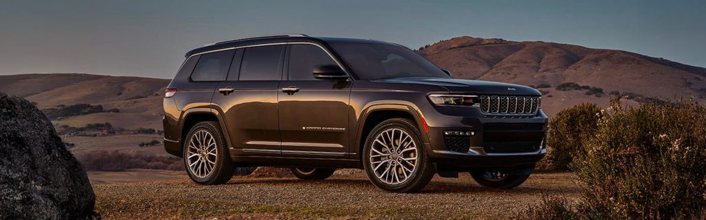 2025 Jeep Grand Cherokee L parked in an open landscape at sunset, showcasing its premium three-row design and rugged SUV styling.